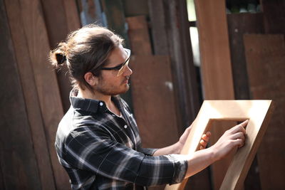 Carpenter holding wooden frame at workshop