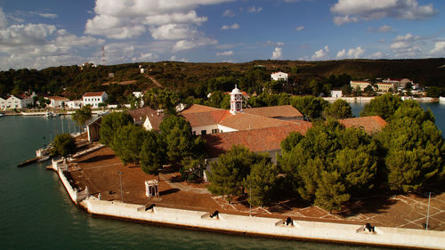 High angle view of buildings amidst trees by sea against sky