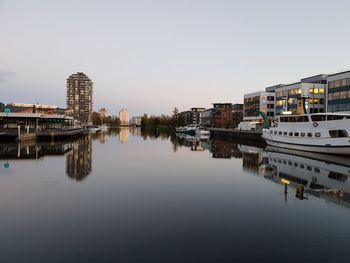 Reflection of buildings in city against clear sky