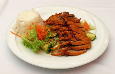 High angle view of peking duck with chop suey and steamed rice served in plate on table