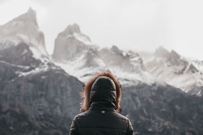 Rear view of woman on snowcapped mountain against sky