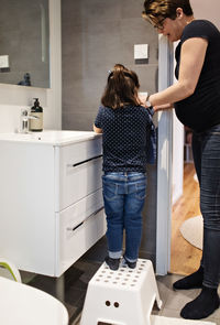 Mother assisting daughter in washing hands at home