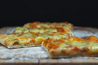 Close-up of pizza on table against black background