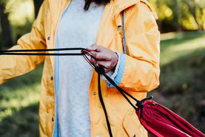 Midsection of woman holding hammock in forest