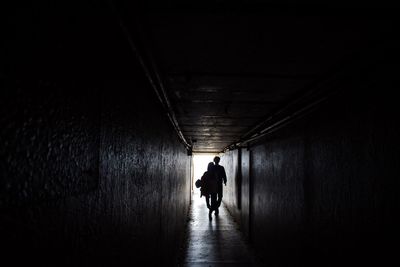 Rear view of woman walking in tunnel