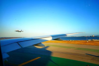 Airplane flying over runway against clear blue sky