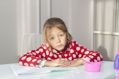 Portrait of girl sitting on table