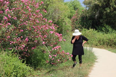 Full length of woman standing by flowering plants