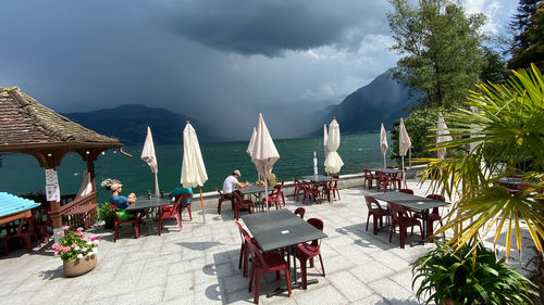 Panoramic view of chairs and tables at beach against sky