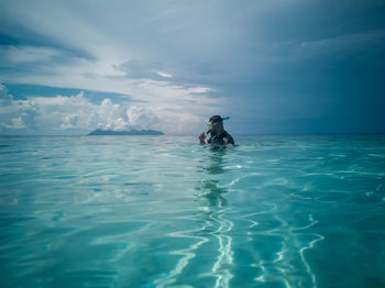 Man swimming in sea against sky