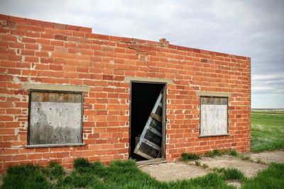 Exterior of abandoned house on field against sky