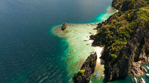 Aerial drone tropical landscape bay with beach and clear blue water surrounded by cliffs. el nido