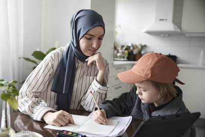 Mother helping son with homework at home