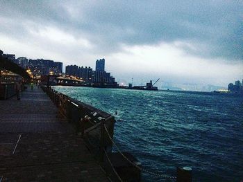 Pier on river against cloudy sky