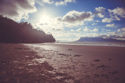 Scenic view of beach against cloudy sky