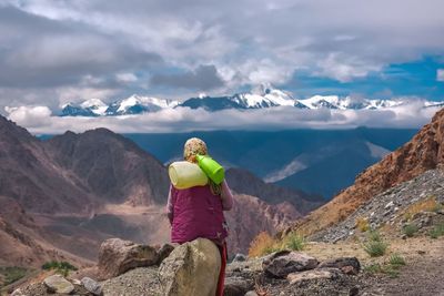 Rear view of man standing on rock against sky