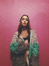 Portrait of woman standing against red wall