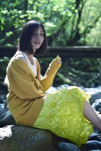 Young woman sitting on yellow leaf