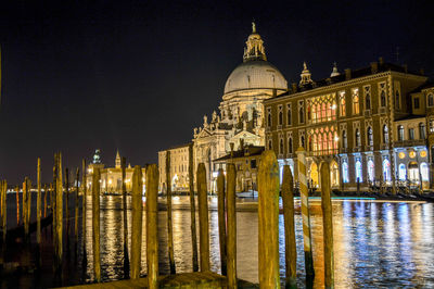 Illuminated santa maria della salute by canal against sky at night