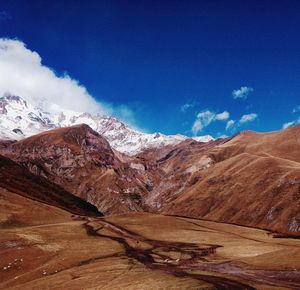 Scenic view of snowcapped mountains against blue sky