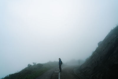 Man on road amidst trees against sky