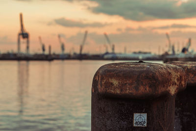 Close-up of rusty metal by sea against sky during sunset