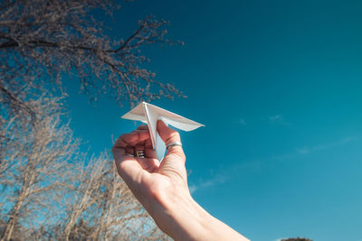 Low section of person holding umbrella against blue sky