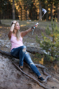 Young woman taking selfie while sitting in forest