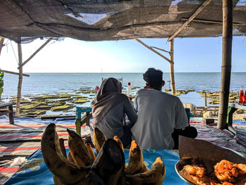 Rear view of people on beach against sky