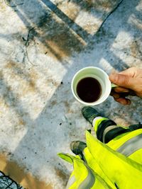 Low section of man holding coffee cup