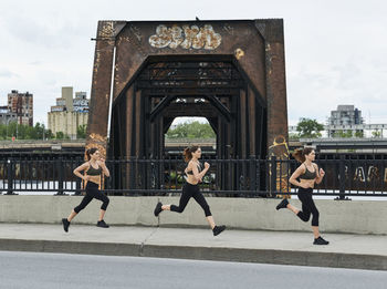 Sporty woman jogging while exercising on bridge in city