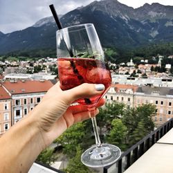 Close-up of hand holding wine glass against built structure