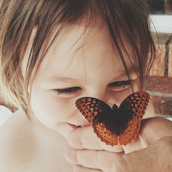 Close-up of girl looking at an orange butterfly