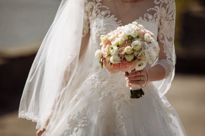 Midsection of bride holding bouquet