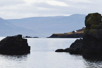 Rock formation by sea against sky