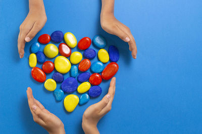 High angle view of hand holding candies over blue background