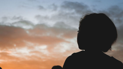 Rear view of silhouette boy against sky during sunset