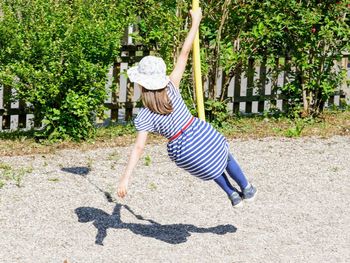 Full length of girl hanging on play equipment at playground