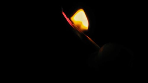 Close-up of burning candle against black background