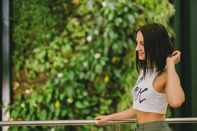 Smiling young woman standing at balcony