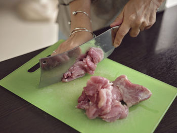 Midsection of man cutting meat on table