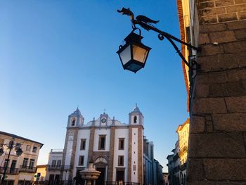 Low angle view of illuminated street light by building against sky