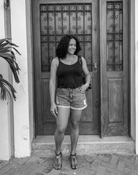 Portrait of young woman standing against wall