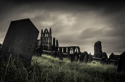 Low angle view of abandoned cemetery against cloudy sky at dusk