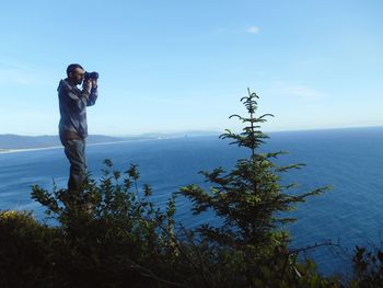 Man photographing sea against sky