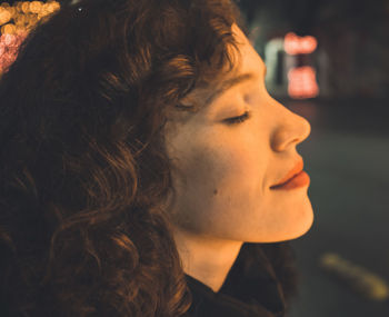 Profile picture of girl with curly hair feeling the warmth of light