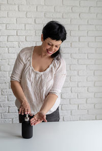 Smiling young woman standing against wall