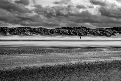 Single person walking alone at a windy beach at bray-dunes in france