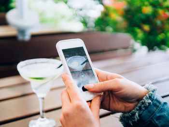 Close-up of woman holding mobile phone and table