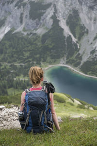 Rear view of backpack woman sitting on mountain